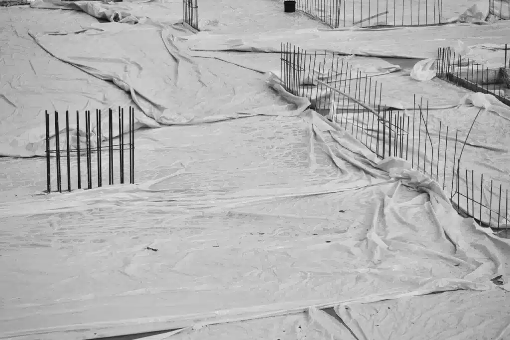 Installation d'une membrane protectrice sur une dalle de béton avant fixation de la lisse basse en bois