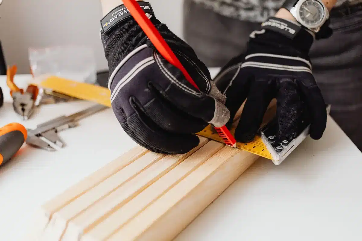 Outils de mesure : mètre ruban, équerre, règle et crayon sur un plan de travail.