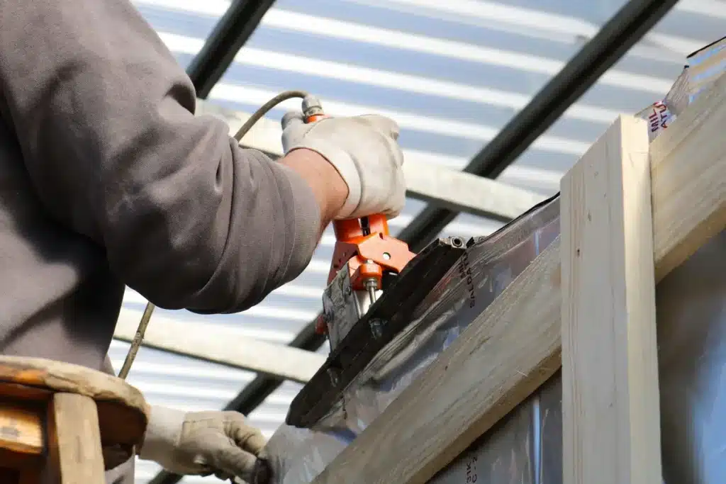 Mains gantées appliquant un joint de mastic avec un pistolet sans fil sur une surface murale