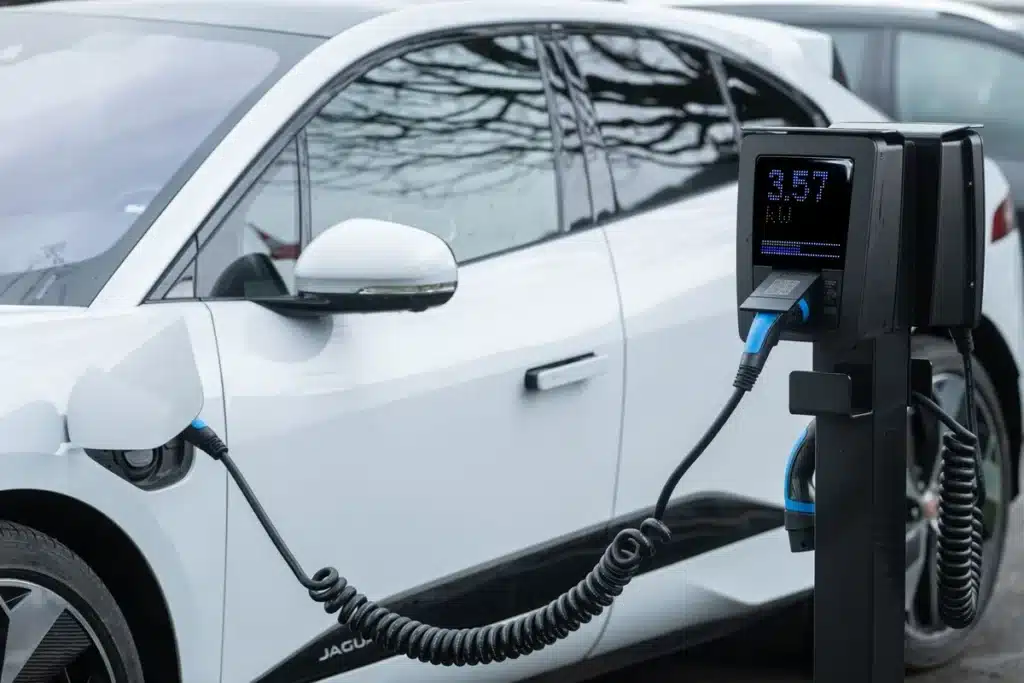 Main de personne branchant un câble de recharge sur une voiture électrique à une borne domestique