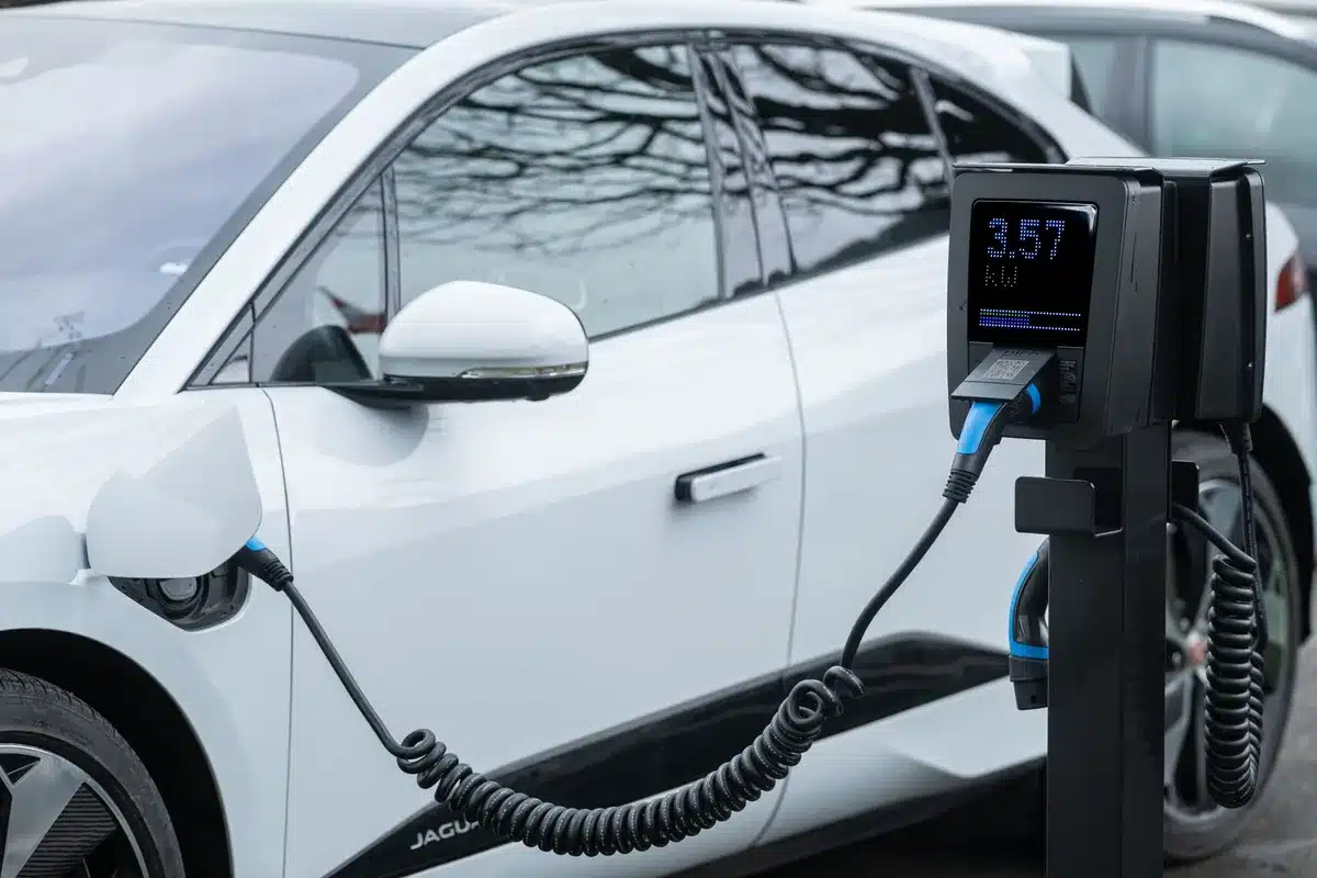 Main de personne branchant un câble de recharge sur une voiture électrique à une borne domestique