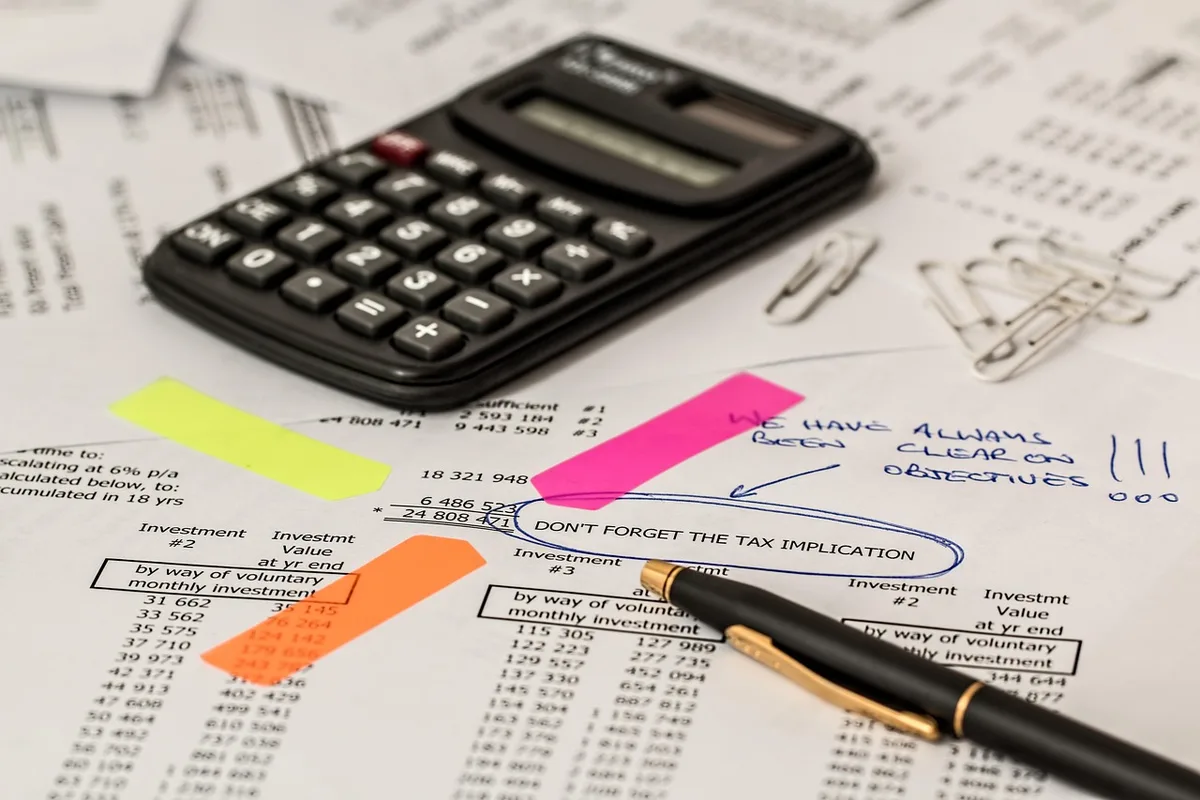 Bureau lumineux avec dossiers ouverts et une calculatrice sur une table, mains feuilletant des papiers