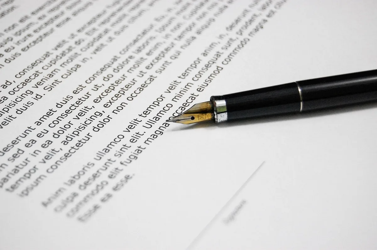 Mandat écrit signé posé sur un bureau avec des mains anonymes