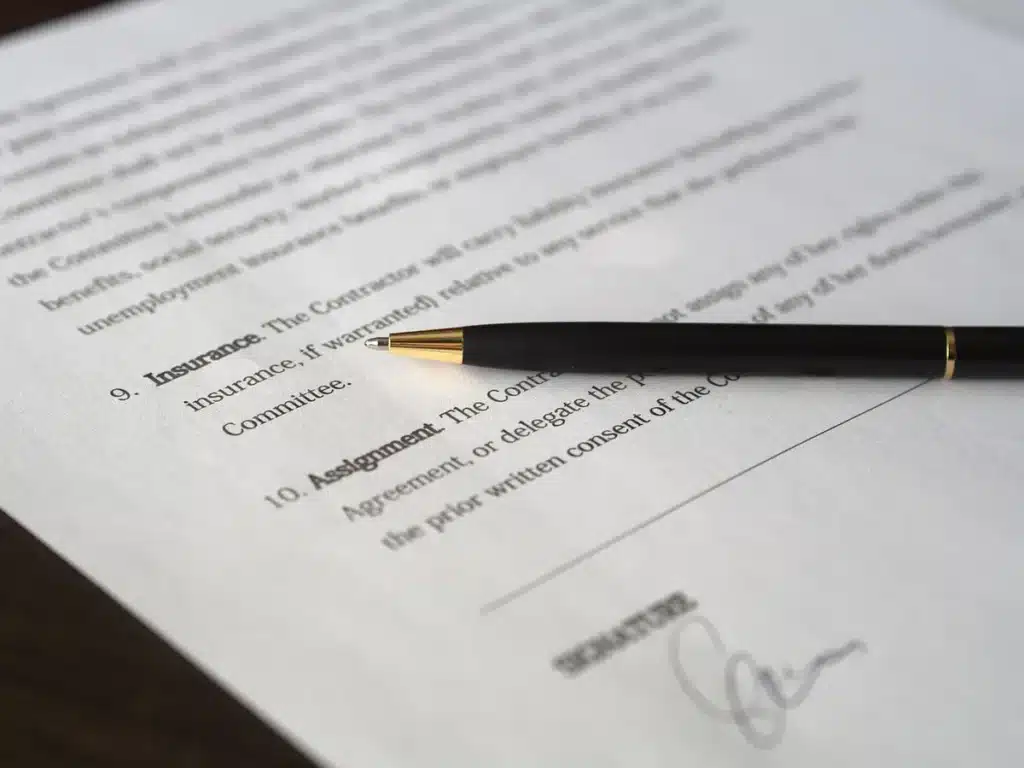 Mains anonymes tenant un dossier de prêt immobilier sur une table ensoleillée