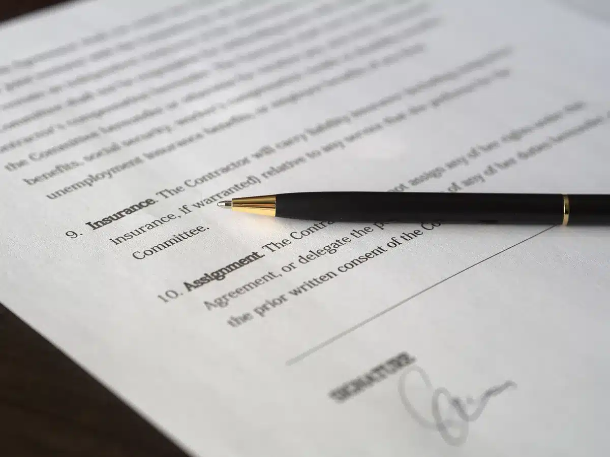 Mains anonymes tenant un dossier de prêt immobilier sur une table ensoleillée