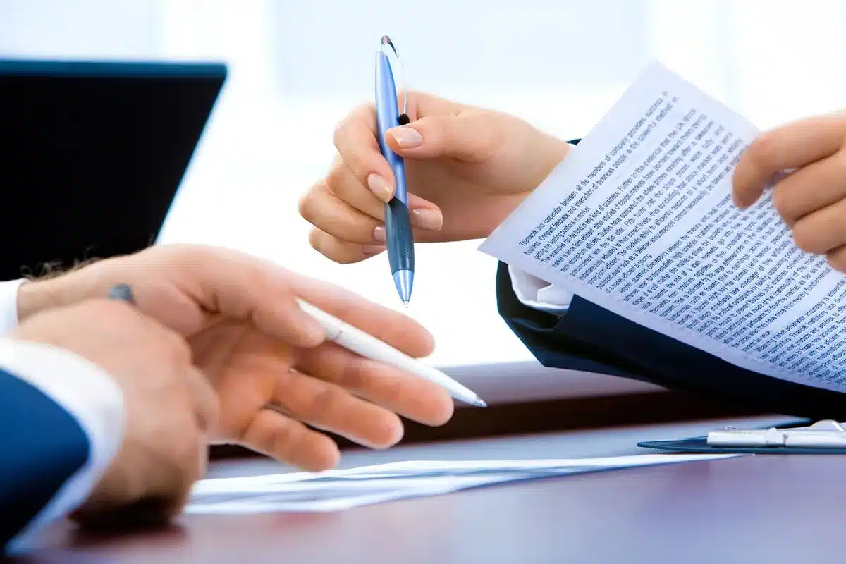 DPE posé sur une table avec des documents et une main feuilletant le rapport