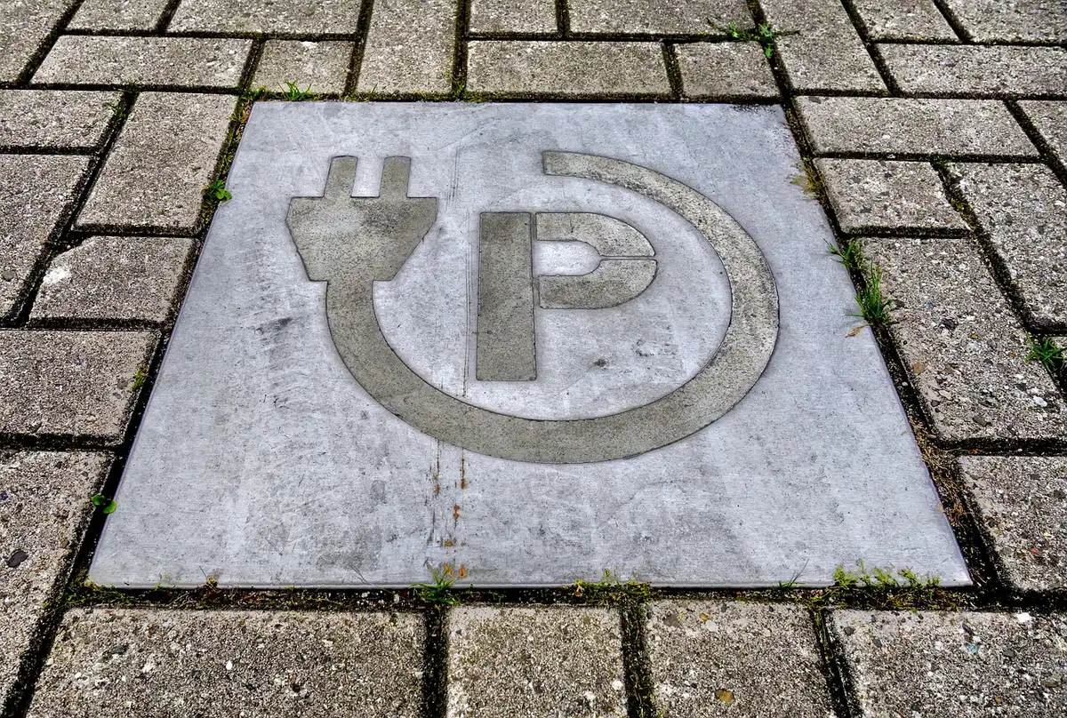 Installateur posant une borne de recharge dans un parking en journée