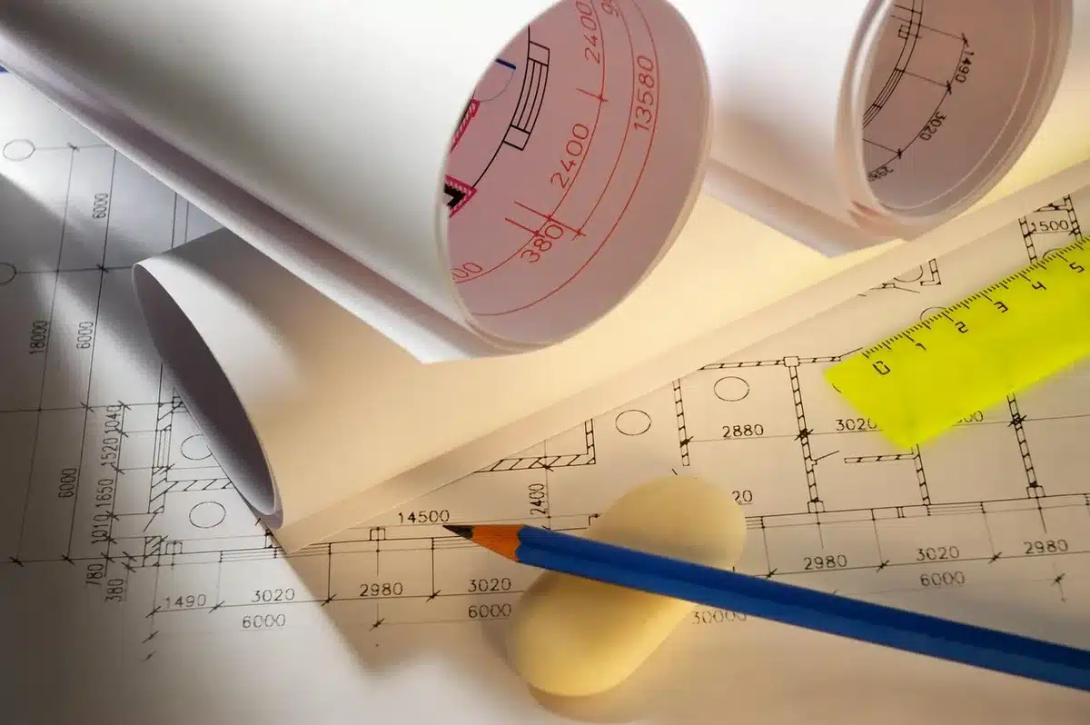 Photo de plans de toiture et documents rassemblés sur une table au soleil