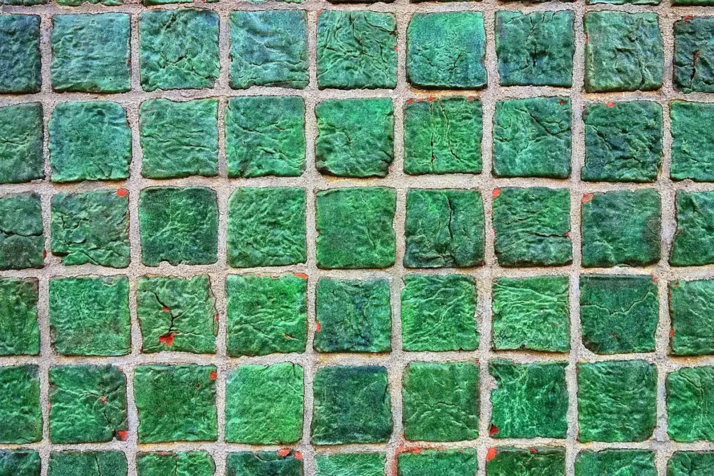 Main gantée utilisant un grattoir en plastique sur un joint de carrelage, lumière du jour