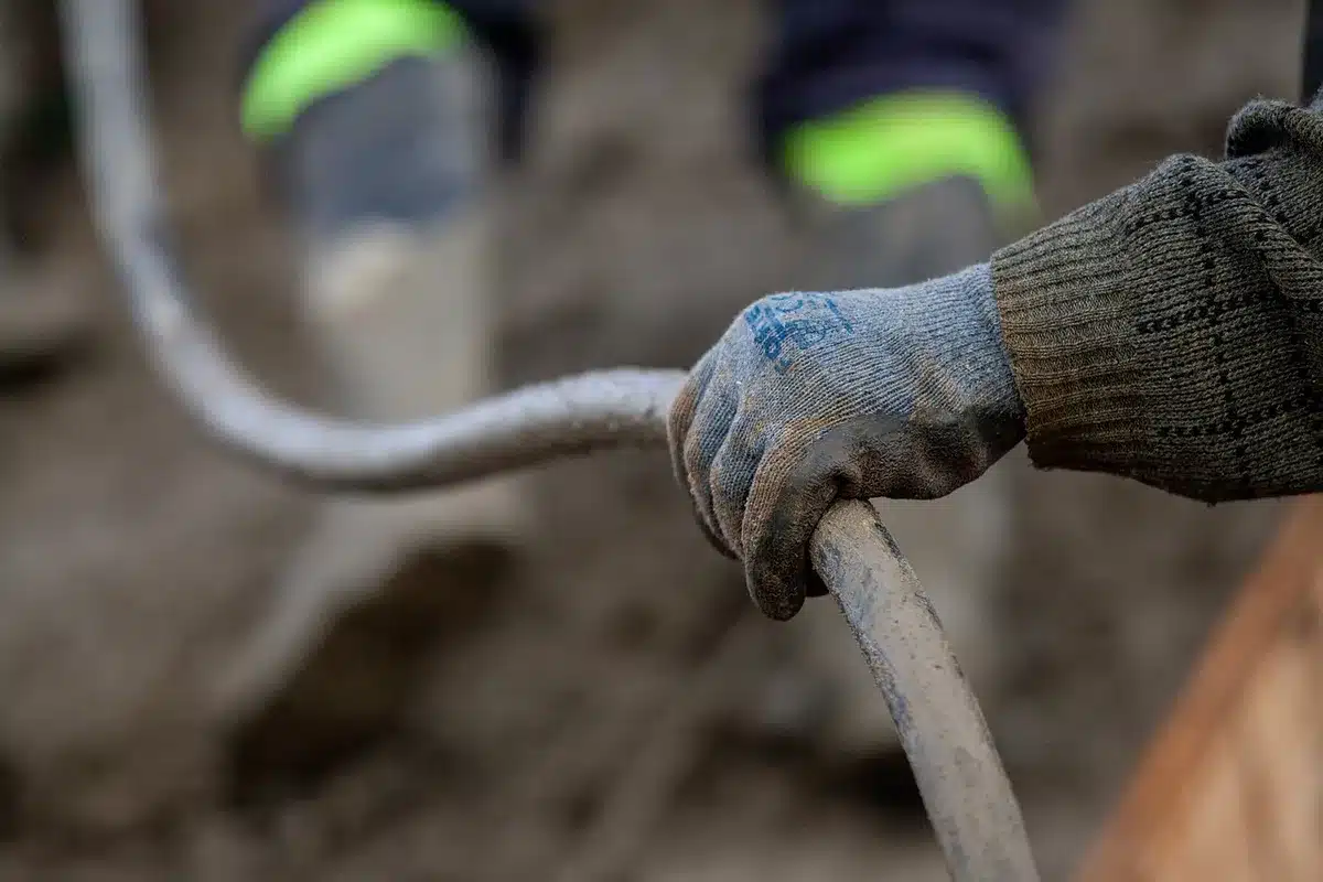 Bricoleur en journée posant un rouleau isolant dans des combles avec gants